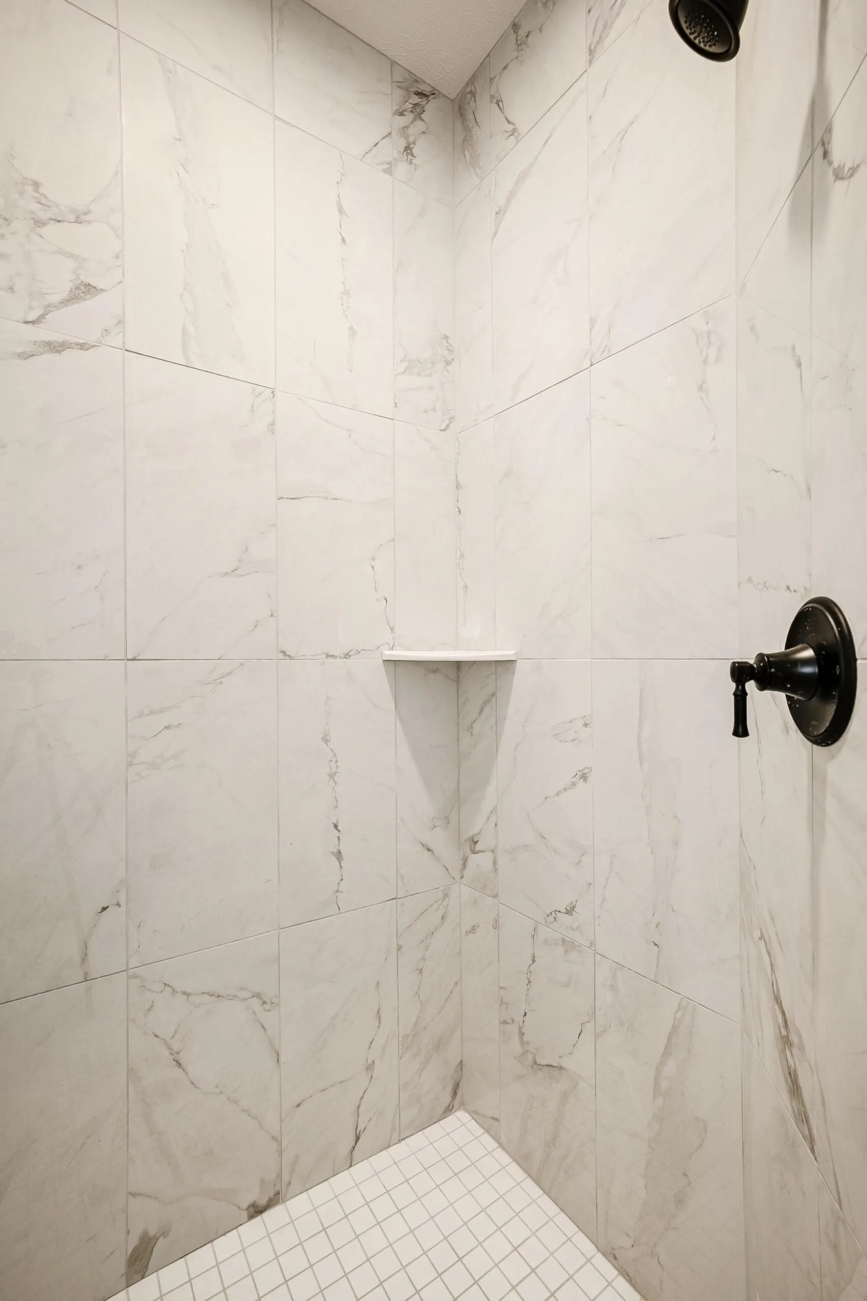 Walk-in shower with marble-look tile and matte black fixtures